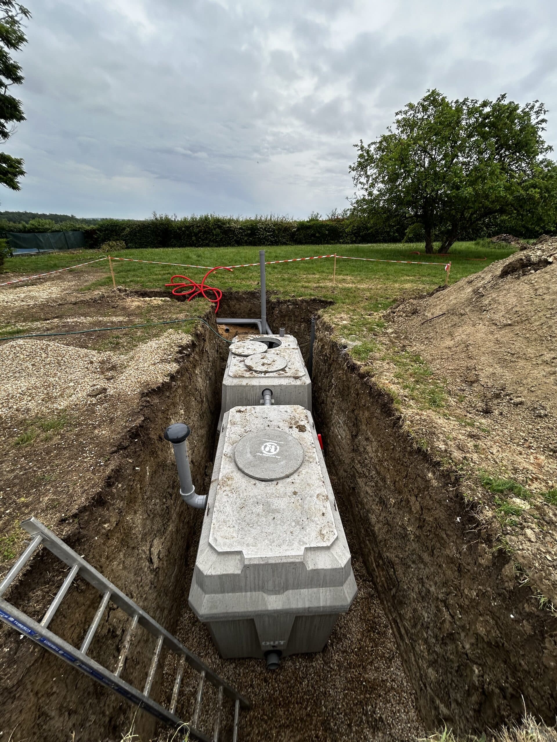 Excavation au Coucher du Soleil : Travaux Lourds et Lumière Dorée Godet d'excavatrice jaune déversant de la terre et des roches au coucher du soleil dans une carrière, créant une forte lueur dorée.