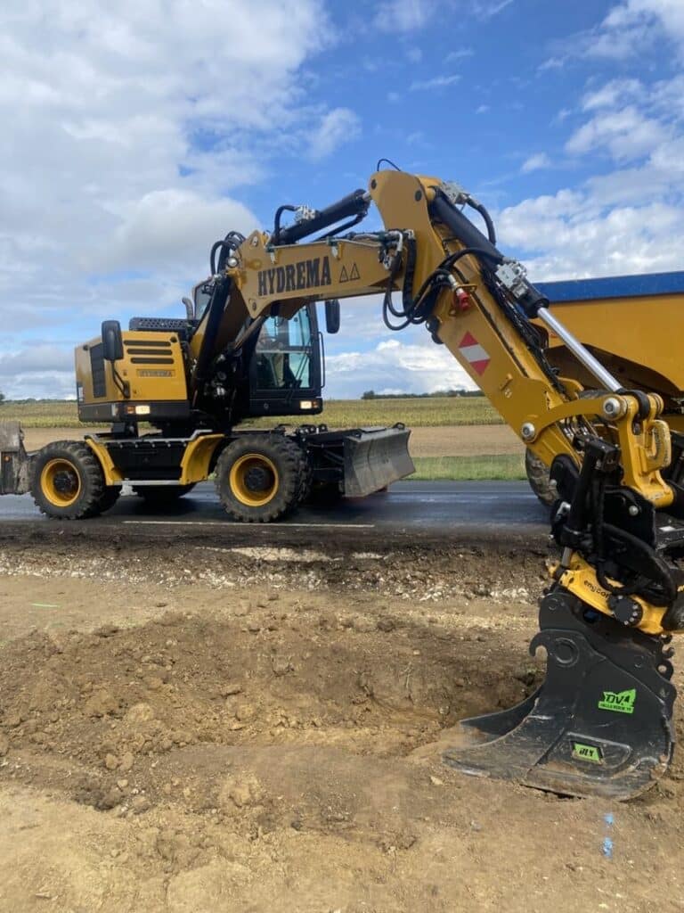 Pelle sur pneus HYDREMA : excavation de tranchée rapide. Excavatrice sur pneus HYDREMA jaune en action creusant une tranchée. Godet DVA DALLA TERRA 10 et attache engcon.